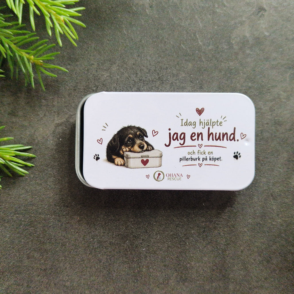 Närbild på liten plåtask med texten Idag hjälpte jag en hund och fick en pillerburk på köpet